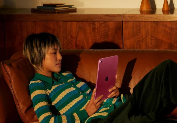 Person relaxing on leather couch using pink iPad tablet at home