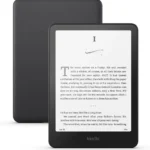 Black Kindle e-reader displaying a page of a novel, shown in front of its matte black back cover.
