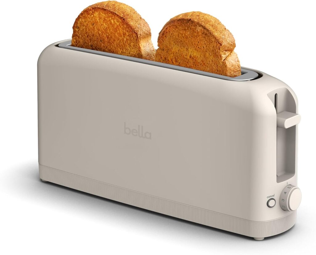 Slim beige Bella 2 Slice Slim Toaster with extra-long slot holding two slices of toasted bread, featuring shade control dial, cancel button, and compact fits-anywhere kitchen design.