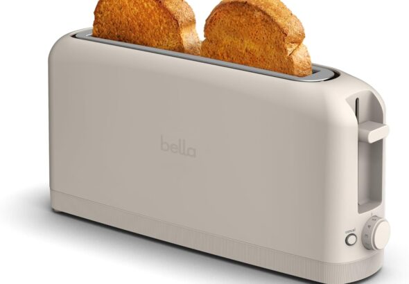 Slim beige Bella 2 Slice Slim Toaster with extra-long slot holding two slices of toasted bread, featuring shade control dial, cancel button, and compact fits-anywhere kitchen design.
