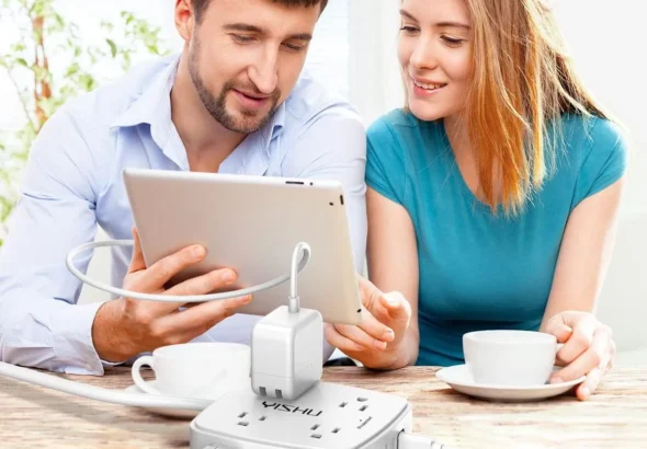 Couple using tablet at table with white 6 ft surge protector power strip featuring 8 outlets and 4 USB ports