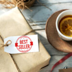 Gift box with best seller tag next to a cup of tea with lemon on a rustic table