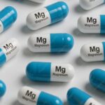 Magnesium supplement capsules in blue and white scattered on a white surface.