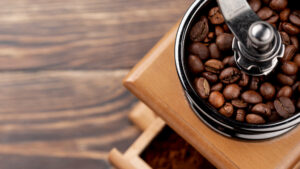 Coffee grinder with fresh whole beans and ground coffee on a kitchen counter