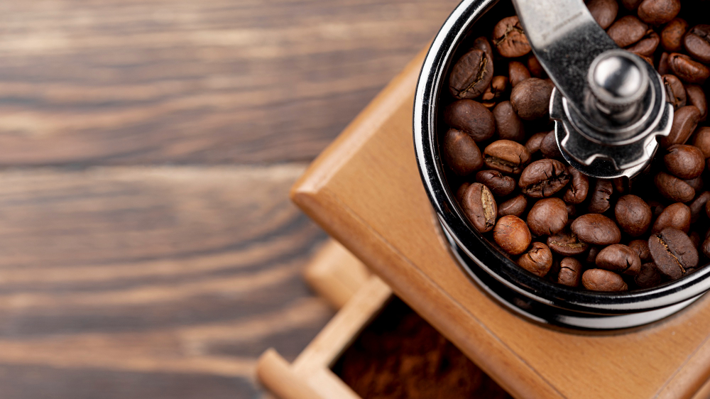 Coffee grinder with fresh whole beans and ground coffee on a kitchen counter