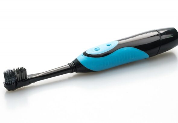 Electric toothbrush with charging base and replacement heads on a bathroom counter