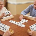 Seniors playing a game of jumbo dominoes with large, high-contrast tiles at a table