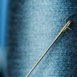 Needle threader tool guiding thread through a needle eye
