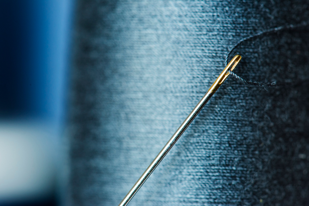 Needle threader tool guiding thread through a needle eye